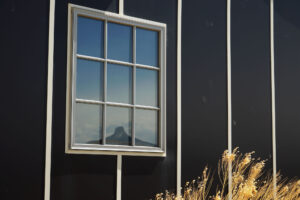 The exterior of the interpretive center has three long buildings created to look like the tar papered barracks. Reflected in the window of one of the buildings is Heart Mountain.